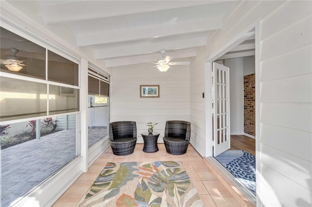 sunroom / solarium with a ceiling fan and beam ceiling