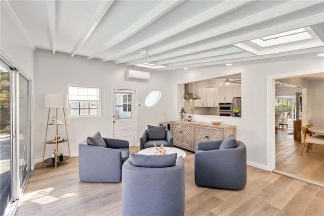 living area with a skylight, a wall mounted AC, light wood-type flooring, beamed ceiling, and baseboards