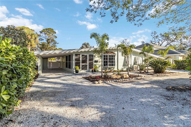 view of front of property with driveway, a sunroom, and a carport