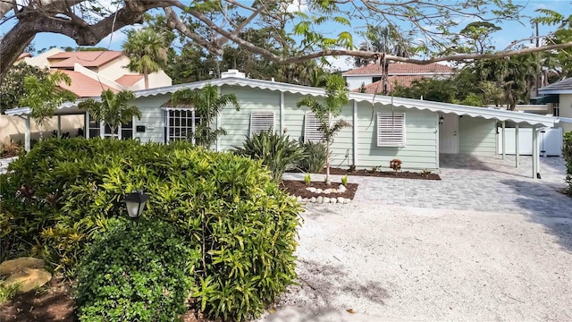 rear view of property with decorative driveway and a carport