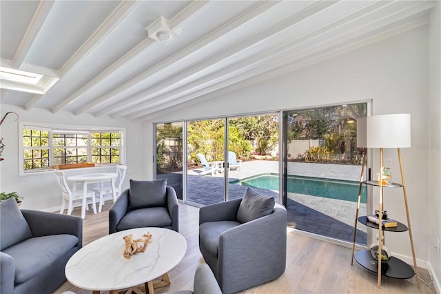 living area with vaulted ceiling with beams, wood finished floors, and baseboards
