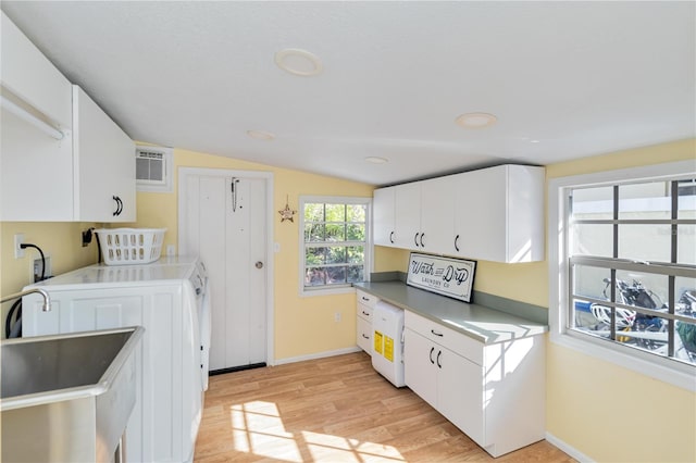 kitchen featuring light wood-style flooring, white cabinetry, vaulted ceiling, a sink, and baseboards