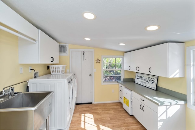 kitchen with washing machine and clothes dryer, white cabinetry, vaulted ceiling, a sink, and light wood-type flooring