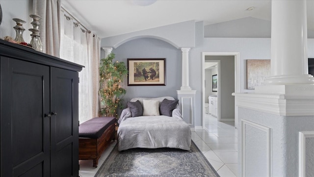 tiled bedroom featuring ensuite bath, lofted ceiling, and decorative columns