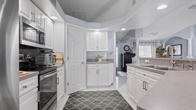 kitchen with sink, ornate columns, white cabinets, and appliances with stainless steel finishes