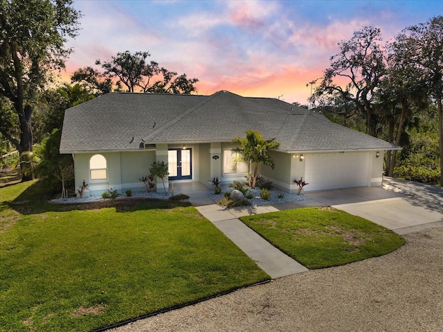 ranch-style home featuring a garage and a yard