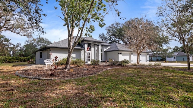 view of front of property featuring an attached garage, driveway, a front lawn, and stucco siding