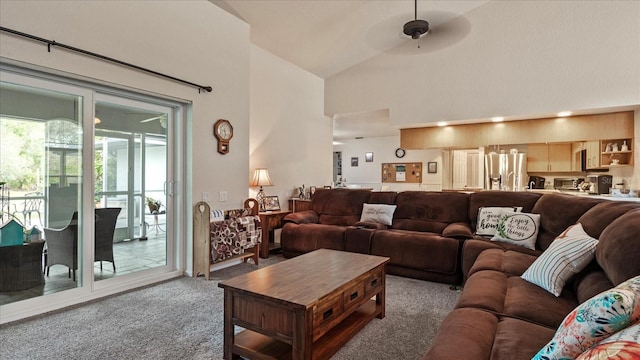 carpeted living room with ceiling fan and high vaulted ceiling