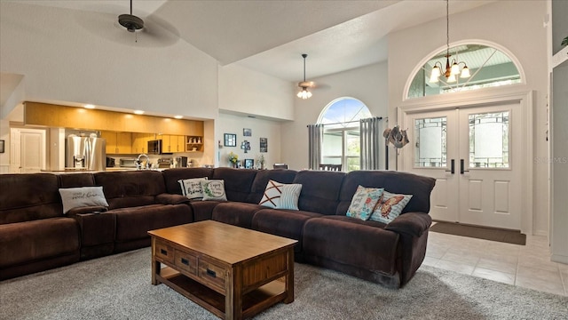 living room featuring french doors, ceiling fan with notable chandelier, high vaulted ceiling, and light tile patterned floors