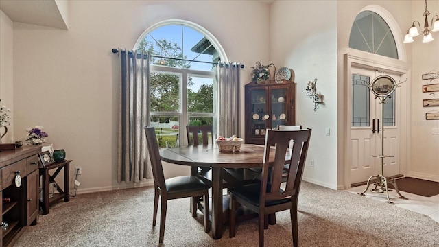 dining area with a high ceiling, carpet flooring, and a notable chandelier