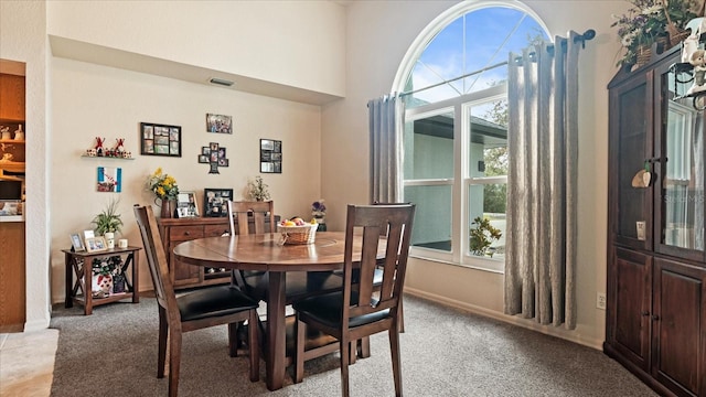 dining room with a towering ceiling and light carpet