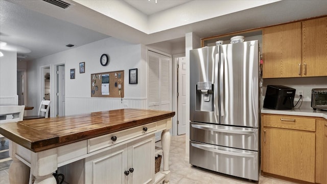 kitchen featuring butcher block countertops and stainless steel refrigerator with ice dispenser