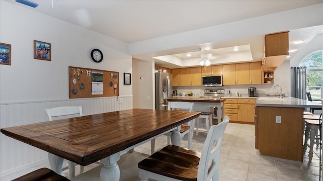 dining space with sink, a tray ceiling, and ceiling fan