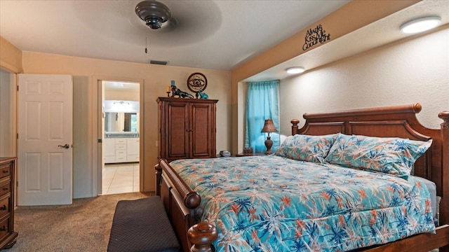 bedroom featuring light carpet, ensuite bath, and ceiling fan