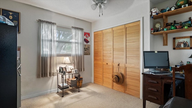 carpeted office space featuring ceiling fan