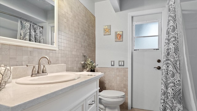 bathroom featuring vanity, toilet, and tile walls