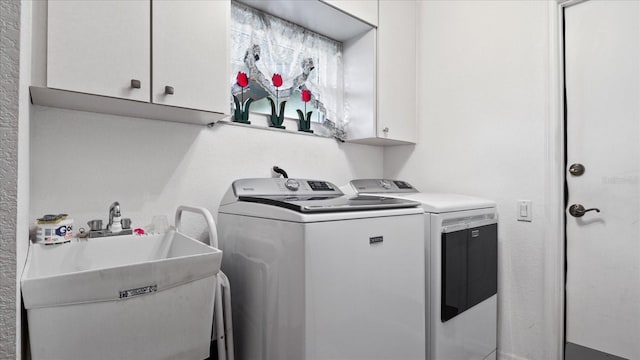 clothes washing area with sink, cabinets, and independent washer and dryer