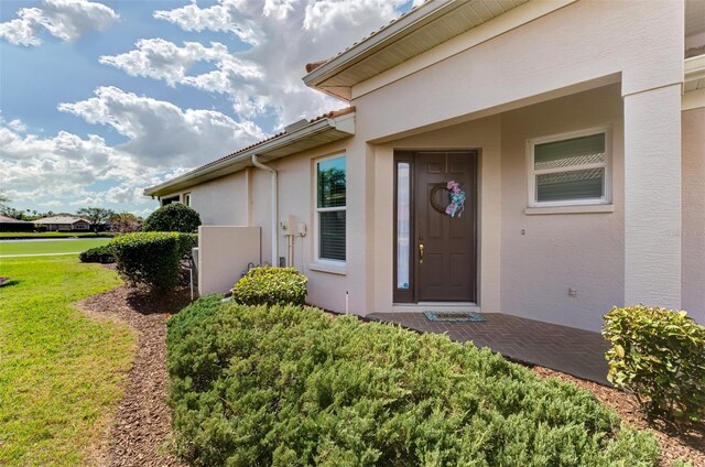 view of exterior entry with a yard