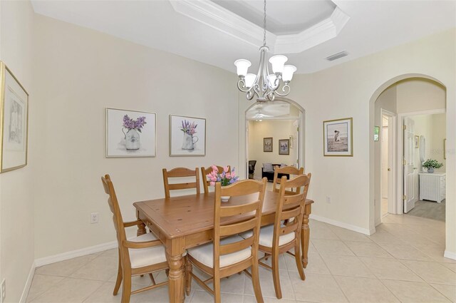 dining area with a raised ceiling, crown molding, light tile patterned floors, and an inviting chandelier