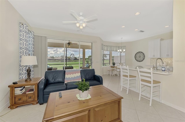 living room with ceiling fan with notable chandelier, sink, and light tile patterned floors