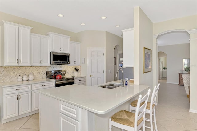 kitchen featuring light tile patterned flooring, appliances with stainless steel finishes, sink, white cabinets, and backsplash