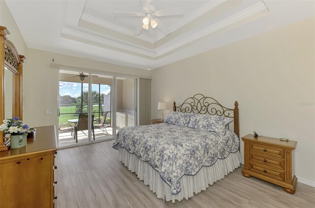 bedroom with crown molding, light hardwood / wood-style flooring, ceiling fan, access to exterior, and a tray ceiling