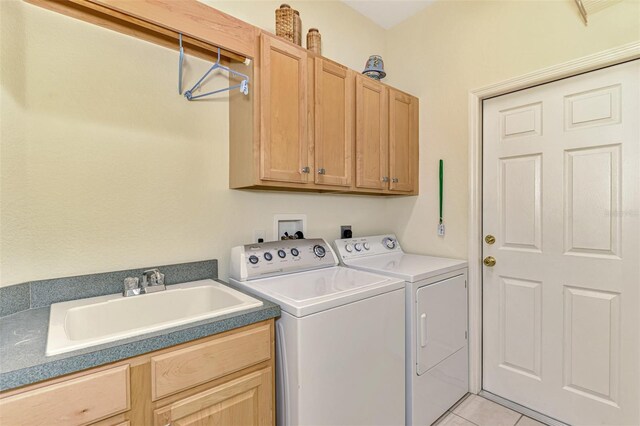 clothes washing area featuring washer and dryer, sink, light tile patterned floors, and cabinets