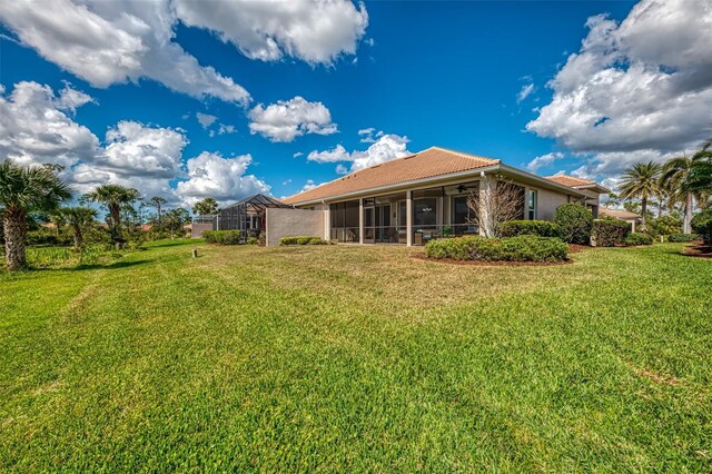 rear view of house with a lanai and a lawn