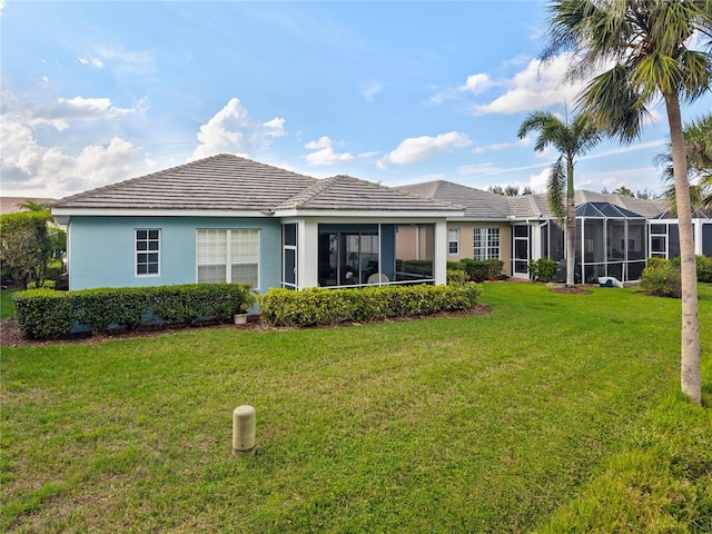 rear view of house featuring a lanai, a tile roof, a lawn, and stucco siding