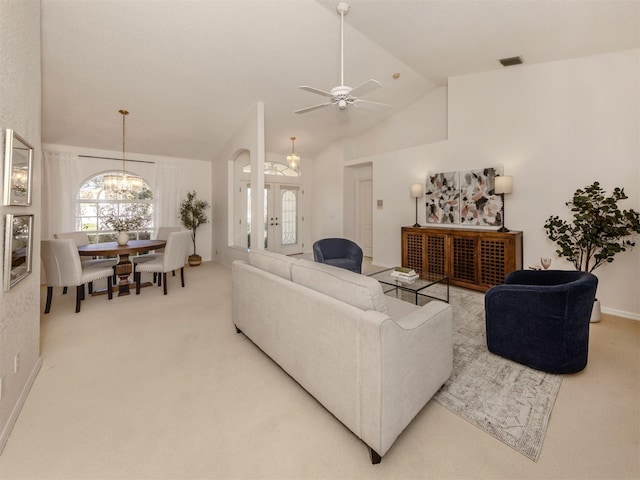 carpeted living room featuring ceiling fan with notable chandelier and high vaulted ceiling