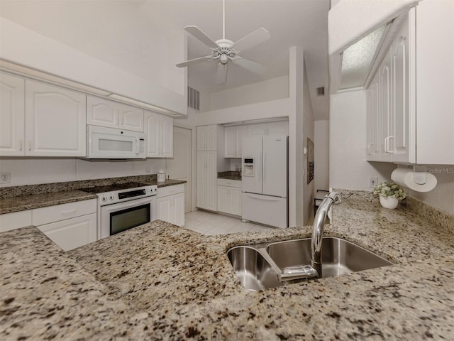 kitchen with sink, white appliances, light tile patterned floors, ceiling fan, and white cabinetry