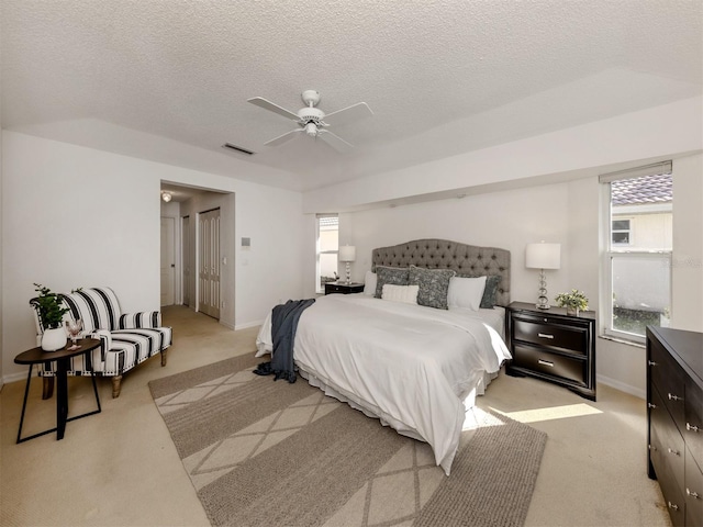 bedroom featuring multiple windows, light carpet, and a textured ceiling