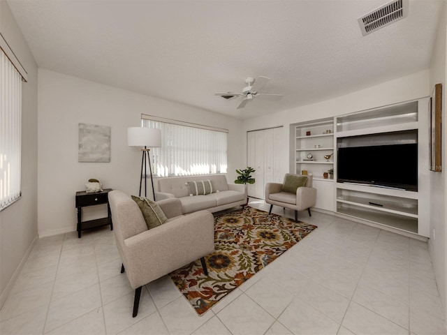 living room with ceiling fan, a textured ceiling, and light tile patterned floors