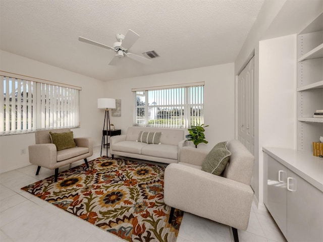 living room featuring ceiling fan, a textured ceiling, and light tile patterned flooring