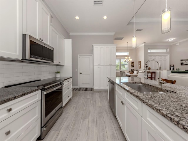 kitchen with white cabinets, appliances with stainless steel finishes, pendant lighting, and a sink