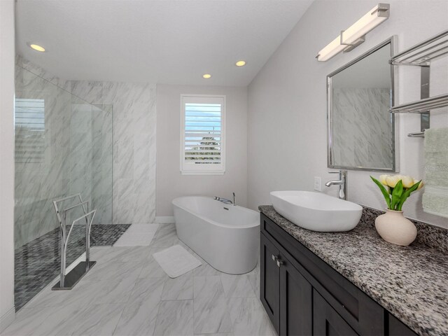 full bath featuring marble finish floor, walk in shower, a freestanding bath, vanity, and recessed lighting