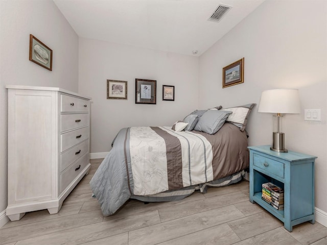 bedroom with light wood-type flooring, visible vents, and baseboards