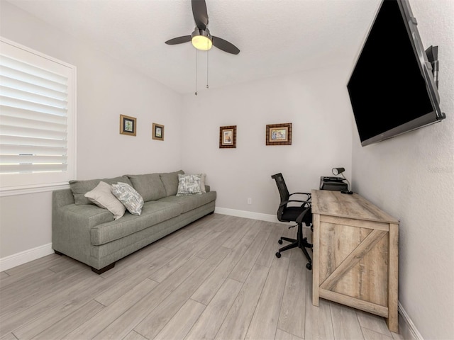 home office with light wood-style flooring, baseboards, and ceiling fan