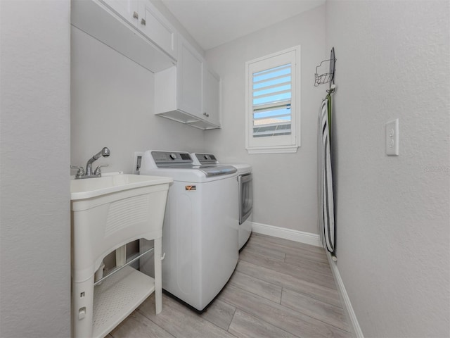 laundry area featuring cabinet space, washing machine and dryer, wood tiled floor, and baseboards