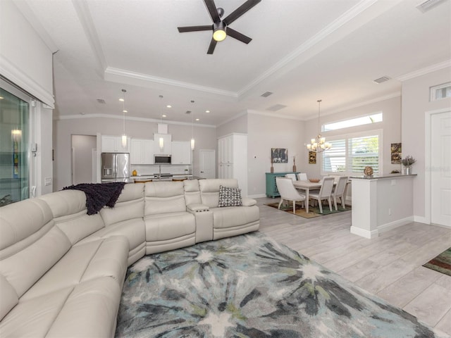 living area featuring baseboards, a tray ceiling, crown molding, light wood-style floors, and ceiling fan with notable chandelier