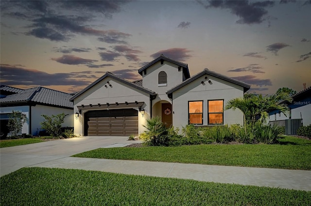 mediterranean / spanish-style house with stucco siding, central air condition unit, concrete driveway, an attached garage, and a front lawn