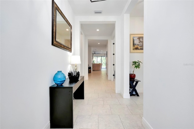 hall featuring light tile patterned floors, visible vents, and baseboards