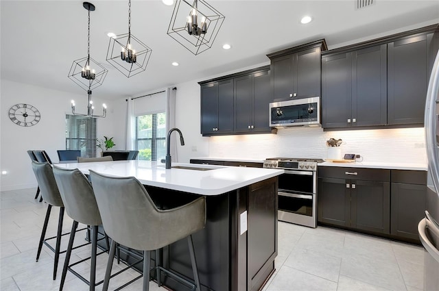 kitchen with a sink, a kitchen breakfast bar, light countertops, appliances with stainless steel finishes, and backsplash