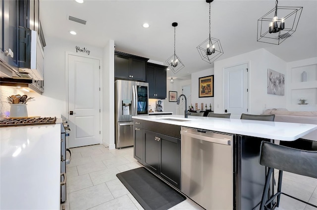 kitchen with a center island with sink, visible vents, appliances with stainless steel finishes, light countertops, and a sink