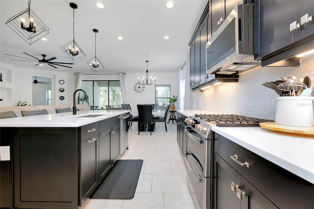 kitchen with pendant lighting, stainless steel appliances, light countertops, open floor plan, and a sink