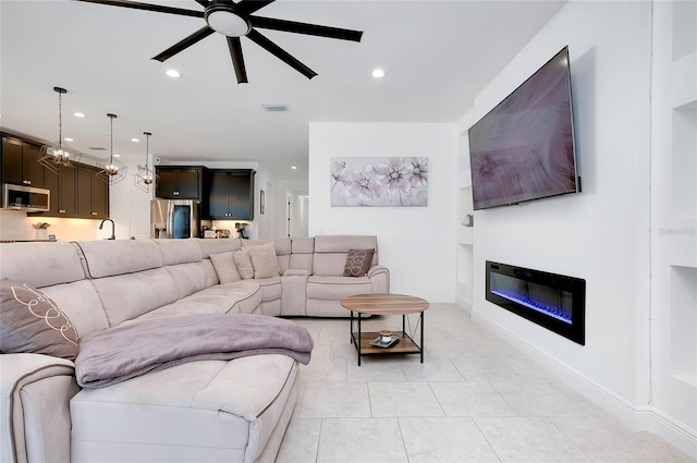 living area featuring a ceiling fan, recessed lighting, a glass covered fireplace, and visible vents