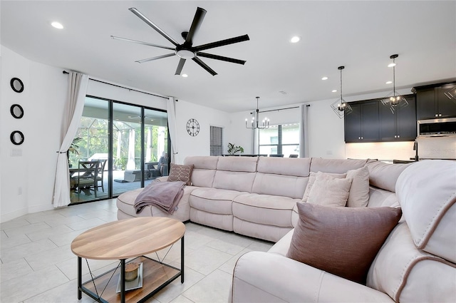 living room featuring ceiling fan with notable chandelier, light tile patterned flooring, baseboards, and recessed lighting