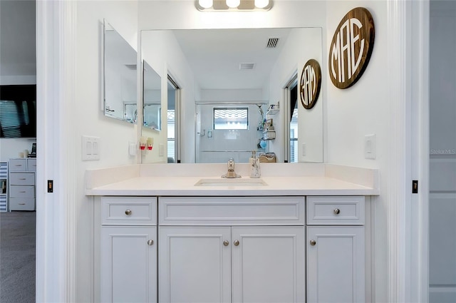 bathroom with visible vents, vanity, and walk in shower