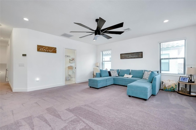 living room with light carpet, a ceiling fan, visible vents, and a wealth of natural light