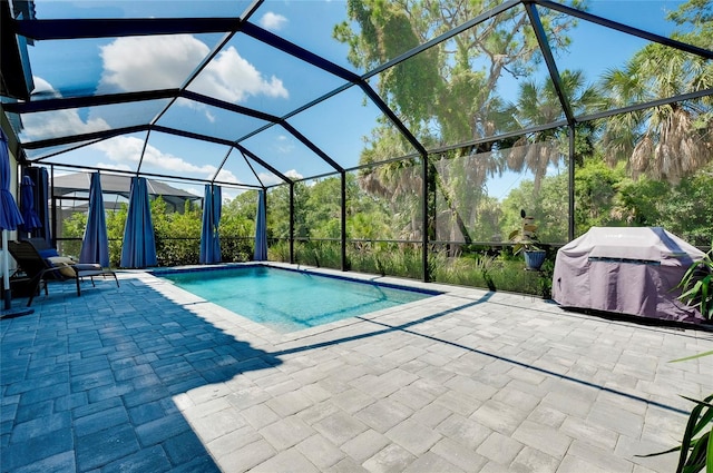 outdoor pool featuring glass enclosure, a patio area, and a grill